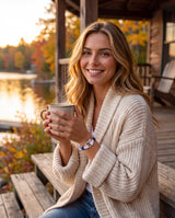 Woman in a cream cardigan on a lake house porch at sunset wearing the white red and blue nautical paracord shackle bracelet