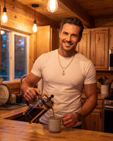 Man pouring coffee in a cozy cabin kitchen wearing the gold layered compass pendant necklace