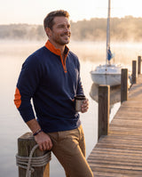 Man on a misty lake dock at sunrise wearing the navy and red nautical paracord shackle bracelet and a quarter-zip pullover