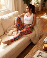 Woman sitting on a sofa in colorful crochet-print leggings