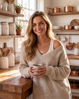 Smiling woman in an oatmeal sweater in a farmhouse kitchen wearing the silver layered compass pendant necklace