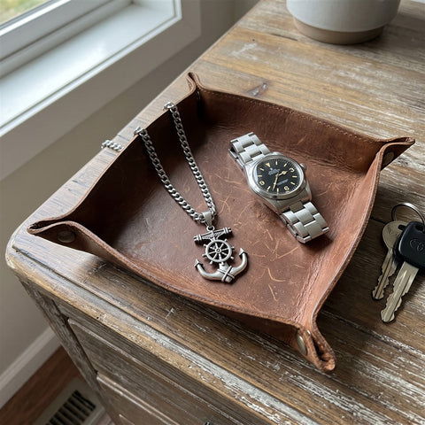 Anchor necklace laid on a leather valet tray next to a watch and keys