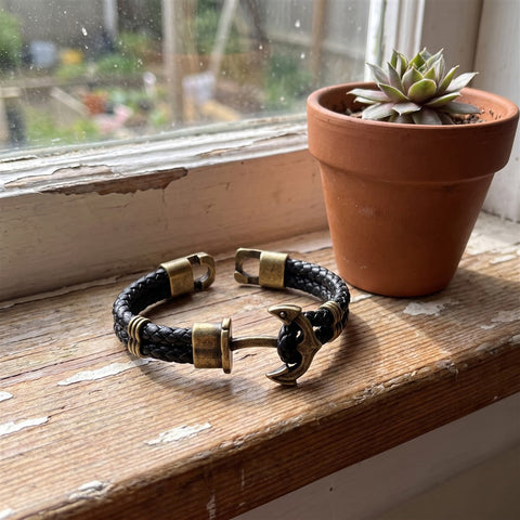 Bronze anchor bracelet on a windowsill with a small plant