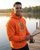 Smiling man in an orange Lucky Anchor crest hoodie fishing from a lake dock