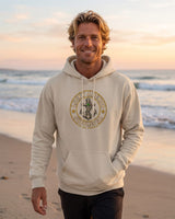 Man in a sand Lucky Anchor crest hoodie walking on a beach at dusk