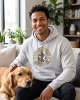 Smiling man in a light grey Lucky Anchor crest hoodie petting a golden retriever on a sofa
