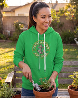Smiling woman in a green Lucky Anchor crest hoodie potting plants in a backyard garden