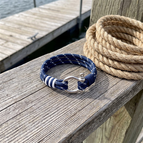 Nautical paracord shackle bracelet coiled on a weathered dock plank