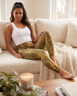 Woman sitting on a sofa in gold metallic woven-print leggings